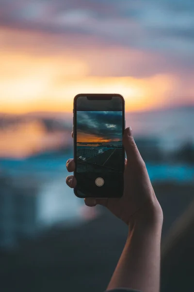Gün batımında denizin fotoğrafını çeken bir akıllı telefon.