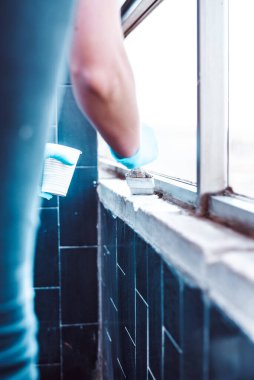 Eldivenli eller beyaz duvarı boyuyor.