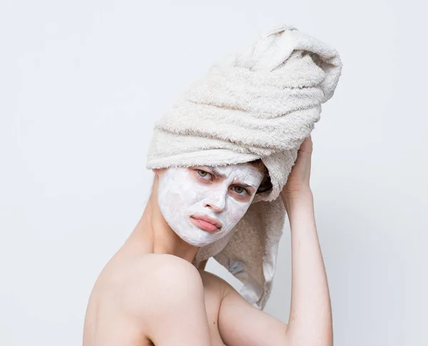 頭にタオルでシャワーを浴び顔にクリームをかけた美しい女性 — ストック写真