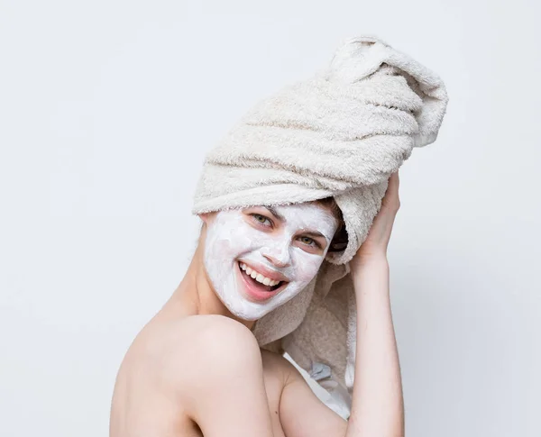 頭にタオルでシャワーを浴び顔にクリームをかけた美しい女性 — ストック写真