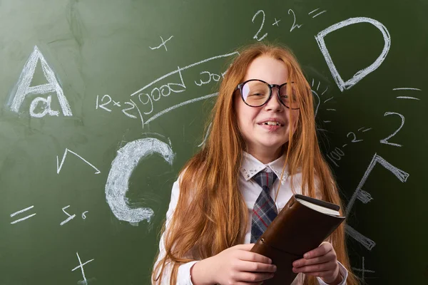Dívka školačka znalosti, dívka u stolu, nošení brýlí na tabuli — Stock fotografie