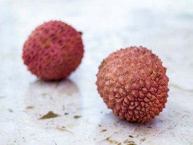 İki taze lychee meyve mermer bir zemin üzerine.