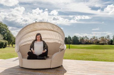 30 yaşındaki hamile kadın, arka planda doğal manzara ile yuvada poz veriyor.