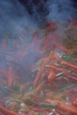 Sebzeler ve bira tavuğu, tahta kaşıkla karıştırılır.