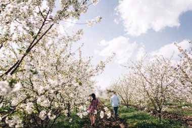 Genç çift çiçek açan bahçede yürüyüş