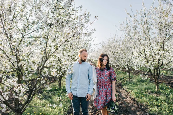 Pareja joven caminando en el jardín floreciente — Foto de Stock