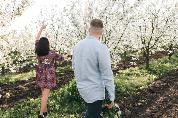 Junges Paar spaziert im blühenden Garten — Stockfoto