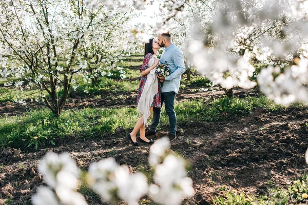 Ungt par promenader i den blommande trädgården — Stockfoto