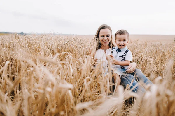 Madre e hijo sentados en el campo de trigo — Foto de Stock