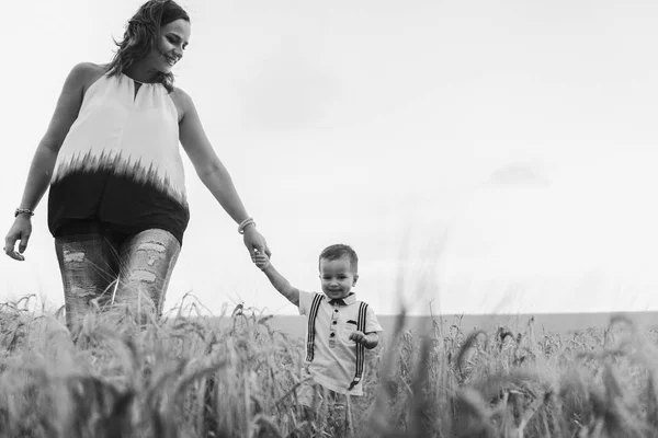 mother and son walking in wheat field