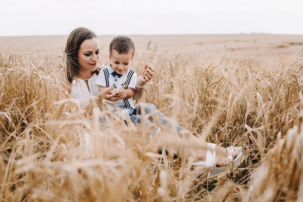Madre e hijo sentados en el campo de trigo — Foto de Stock