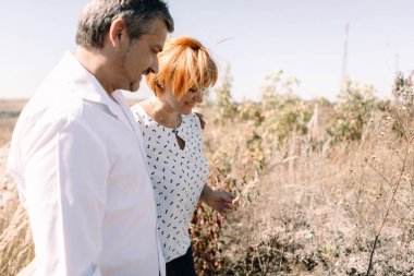 Orta yaşlı çift sarı çim yürür