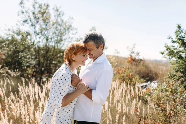 Casal de meia-idade caminha na grama amarela — Fotografia de Stock