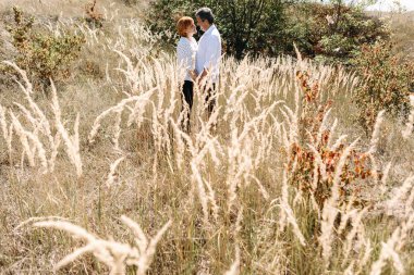 Orta yaşlı çift sarı çim yürür