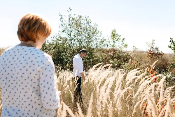 Orta yaşlı çift sarı çim yürür