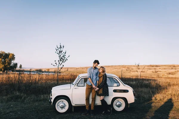 Couple by retro white car in field — Stock Photo, Image