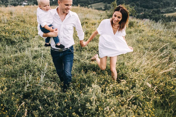 Familia joven caminando en el prado — Foto de Stock