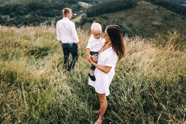 Jeune famille marchant dans la prairie — Photo