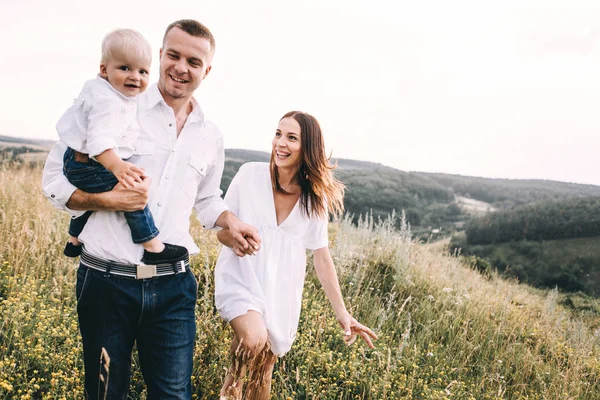 Ung familj promenader i äng — Stockfoto