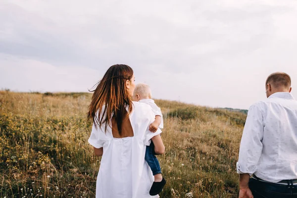 Jeune famille marchant dans la prairie — Photo