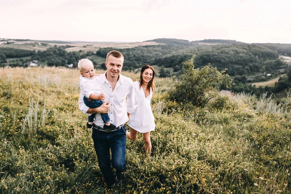 Ung familj promenader i äng — Stockfoto