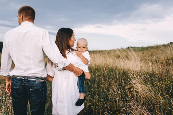 Jeune famille marchant dans la prairie — Photo