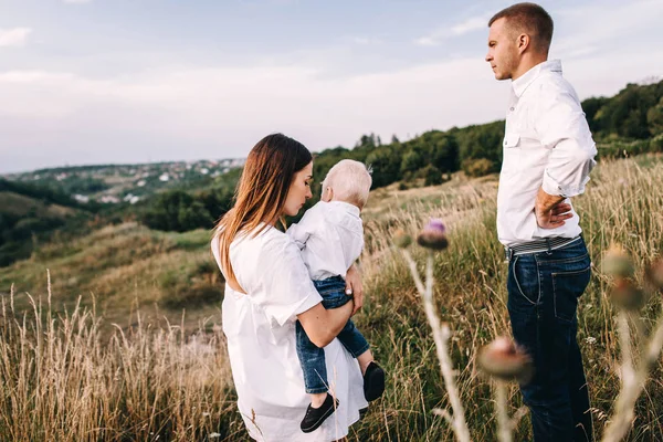 Keluarga muda berjalan di padang rumput — Stok Foto