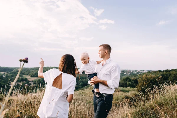 Familia joven caminando en el prado — Foto de Stock