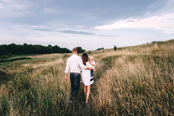 Ung familj promenader i äng — Stockfoto