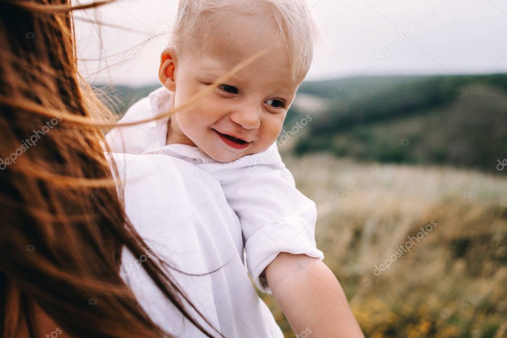 Young beautiful mother with a son in meadow