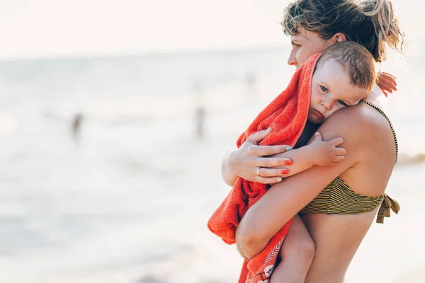 Bambino tra le braccia di sua madre in spiaggia — Foto Stock