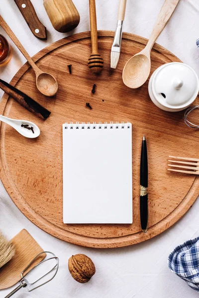 Кухонне начиння, блокнот і ручка на круглому дерев'яному пні — стокове фото