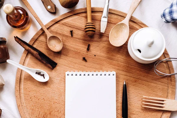 Utensilios de cocina, cuaderno y bolígrafo en tronco de madera redonda —  Fotos de Stock