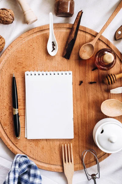 Кухонне начиння, блокнот і ручка на круглому дерев'яному пні — стокове фото