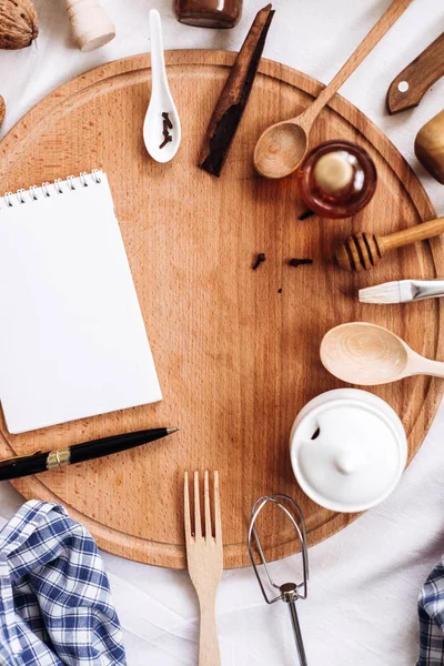 Utensilios de cocina, cuaderno y bolígrafo en tronco de madera redonda —  Fotos de Stock