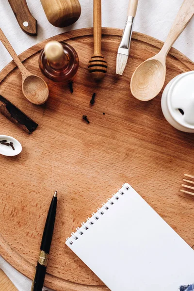 Utensilios de cocina, cuaderno y bolígrafo en tronco de madera redonda —  Fotos de Stock