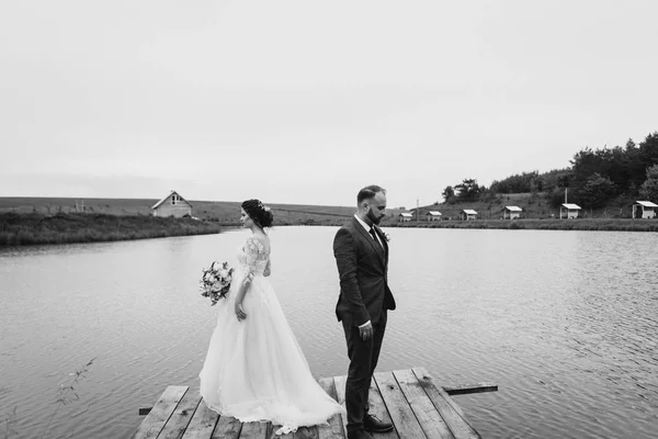 Os recém-casados caminham perto do lago no dia do casamento — Fotografia de Stock