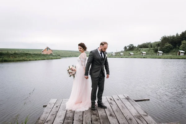 Recién casados caminan cerca del lago el día de su boda —  Fotos de Stock