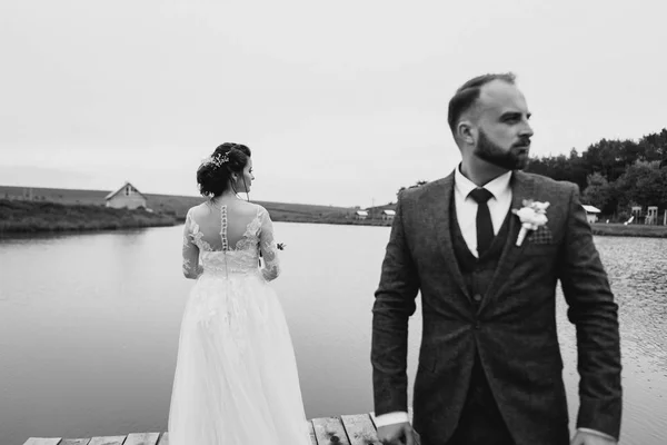 Os recém-casados caminham perto do lago no dia do casamento — Fotografia de Stock