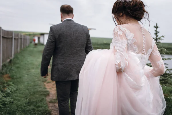 Recién casados caminan cerca del lago el día de su boda —  Fotos de Stock