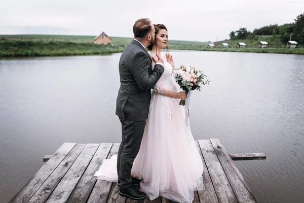 Os recém-casados caminham perto do lago no dia do casamento — Fotografia de Stock