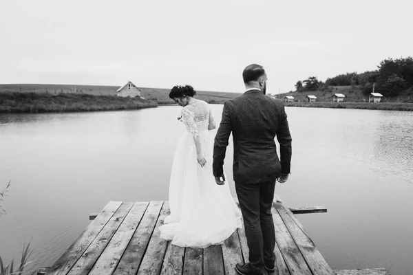 Recién casados caminan cerca del lago el día de su boda —  Fotos de Stock