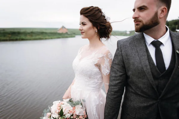 Recién casados caminan cerca del lago el día de su boda —  Fotos de Stock