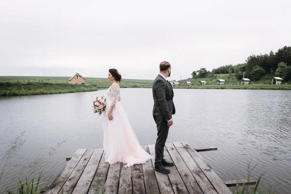 Recién casados caminan cerca del lago el día de su boda — Foto de Stock