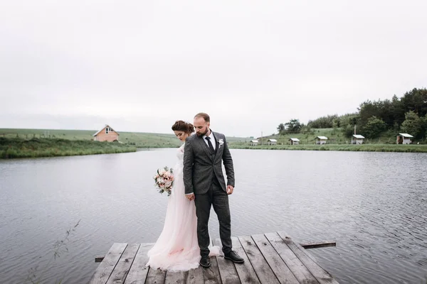 Nygifta promenad nära lake på deras bröllopsdag — Stockfoto