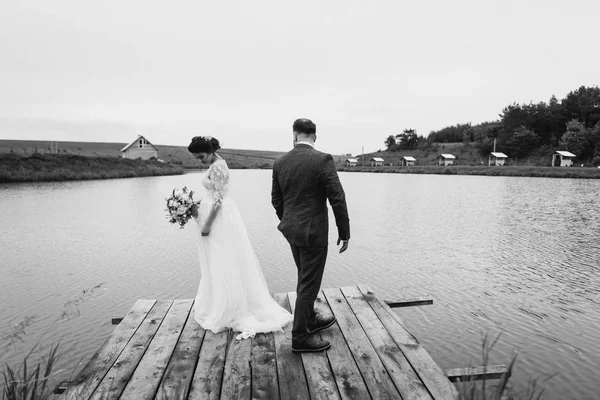 Nygifta promenad nära lake på deras bröllopsdag — Stockfoto