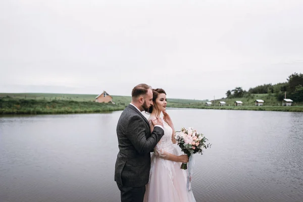 Recién casados caminan cerca del lago el día de su boda —  Fotos de Stock