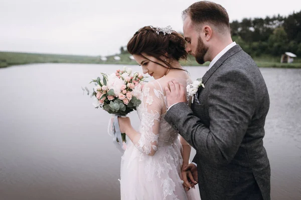 Nowożeńcy spacerem, w pobliżu jeziora w dniu ślubu — Zdjęcie stockowe