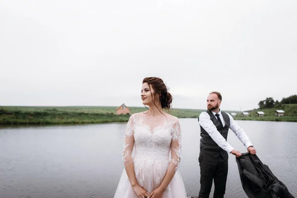 Nygifta promenad nära lake på deras bröllopsdag — Stockfoto