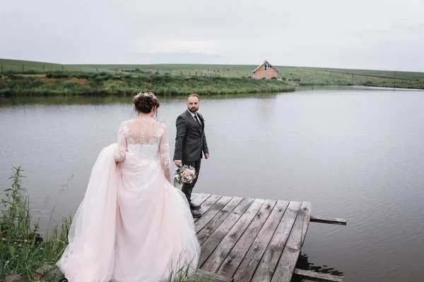 Recién casados caminan cerca del lago el día de su boda —  Fotos de Stock